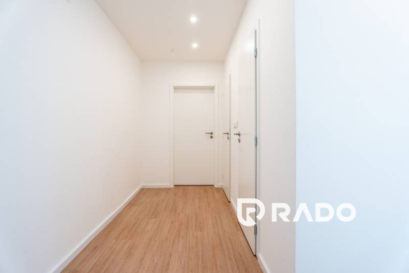 A bright hallway with wooden flooring and white doors in a 3-room apartment.