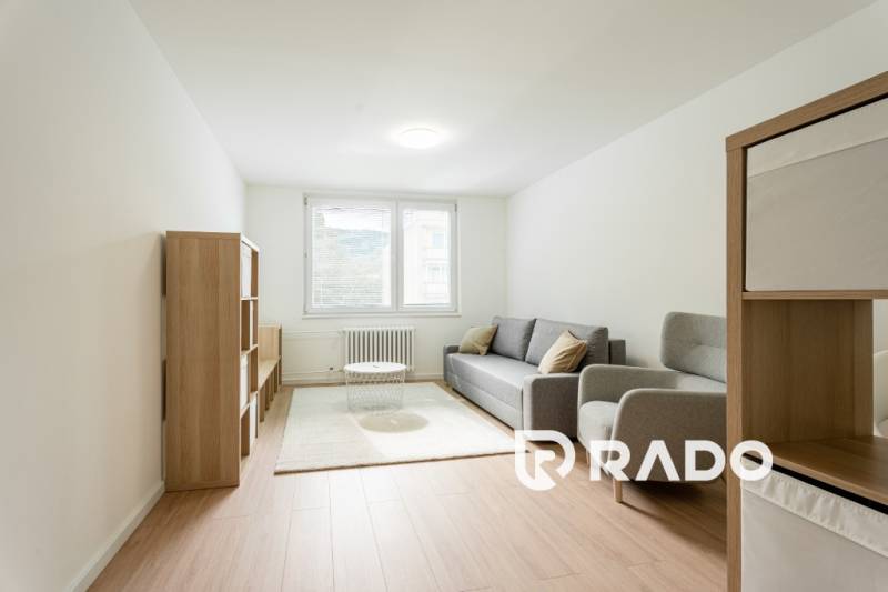 Living room with a light sofa and wooden shelves in a 3-room apartment.