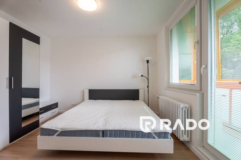 Bright bedroom in a 3-room apartment with a bed, wardrobe, and a balcony window.