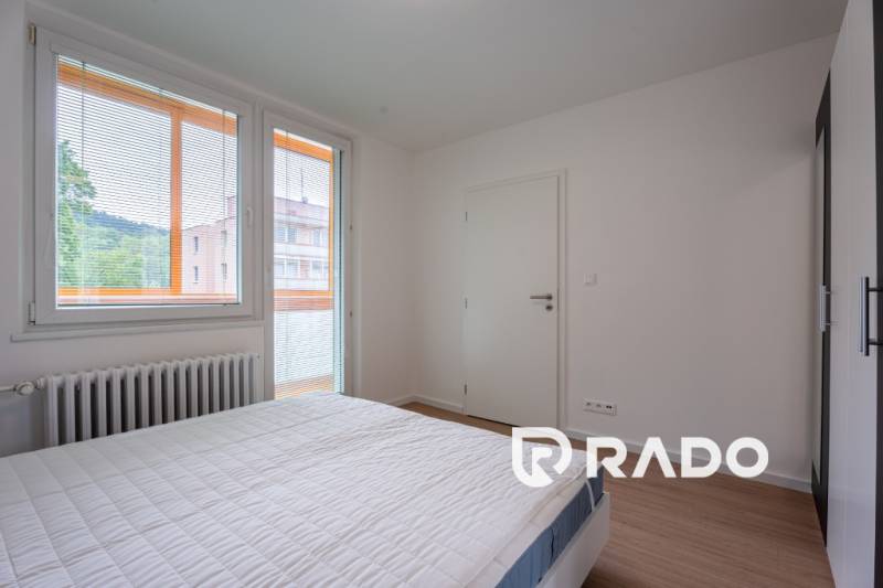 Bedroom in a 3-room apartment with a bed, windows, and a radiator, equipped with blinds.