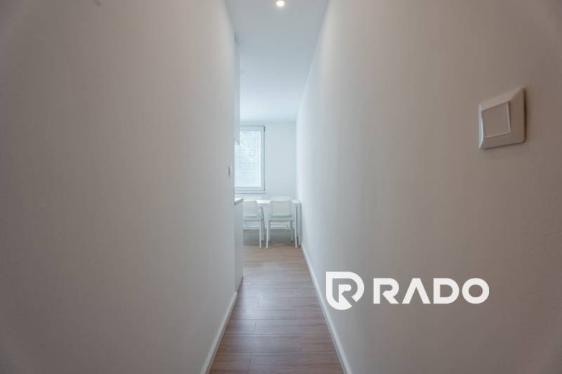 A narrow hallway leading to the dining room in a 3-room apartment with wooden flooring.