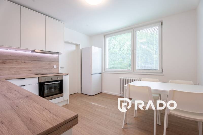 A kitchen in a 3-room apartment with white furniture and a table, wooden details.