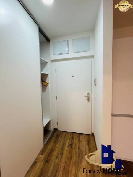 Hallway in a one-room apartment with a shoe cabinet and white doors, wooden floor.