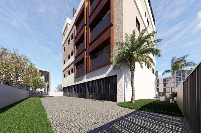 Apartment building in San Pedro del Pinatar with palm trees, lawn, and paved driveway.