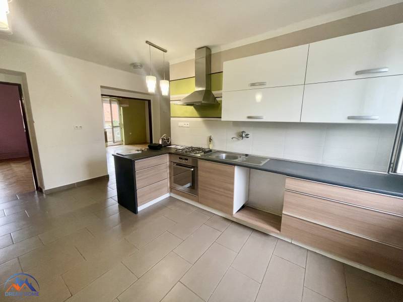A kitchen in a 3-room apartment with a cooktop, white and wooden cabinets.