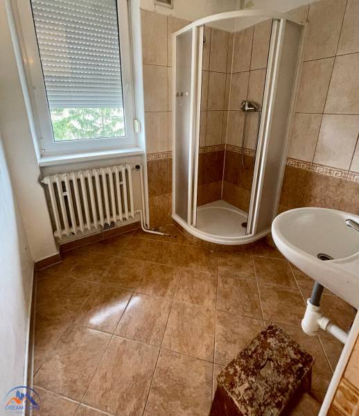 A bathroom in a 3-room apartment with a corner shower and a window.