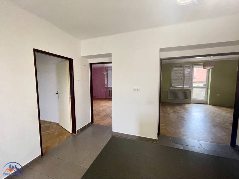 The interior of a 3-room apartment with wooden flooring and a room with a balcony.