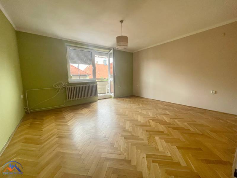 A room with parquet floors and an open balcony in a 3-room apartment.