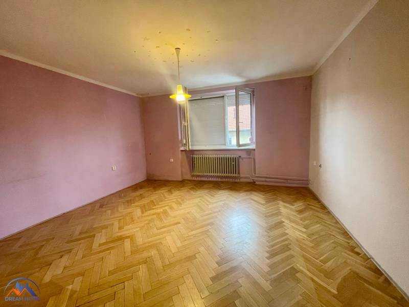 A room with a parquet floor and purple walls in a three-room apartment.