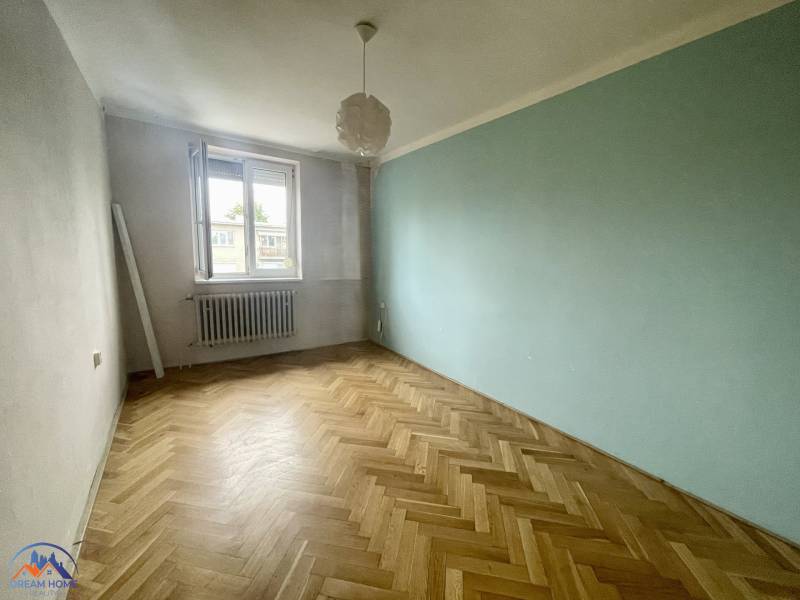 An empty room with parquet flooring and an open window in a 3-room apartment.