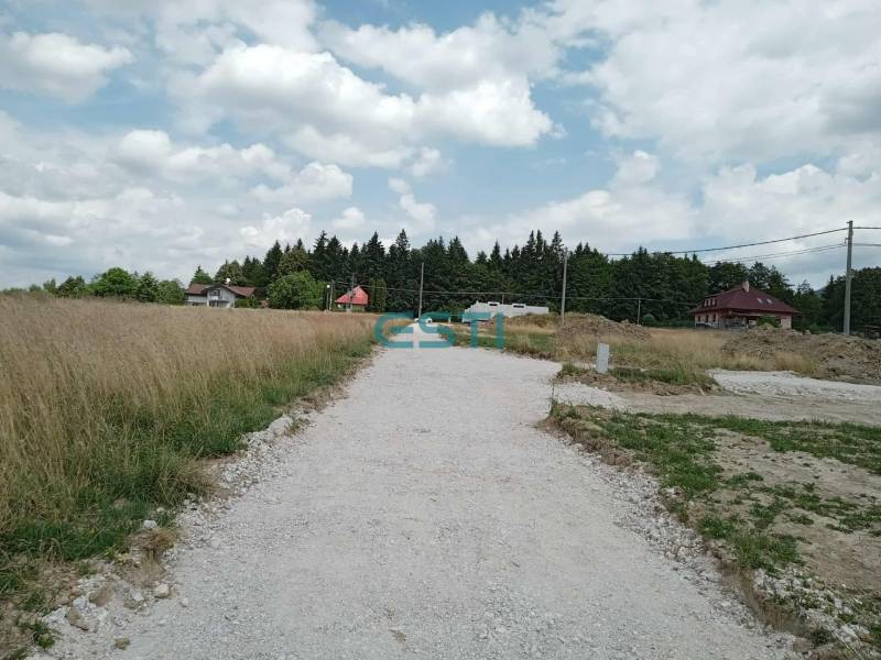The path leads through plots - housing in Kunerad, surrounded by houses and trees.