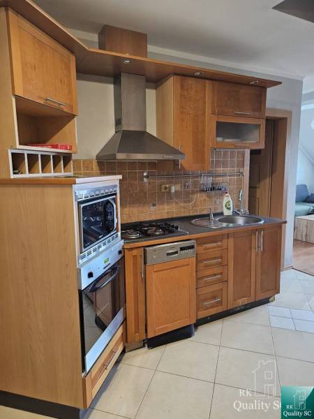 A kitchen with wooden cabinets in a 3-room apartment, containing a stove and a dishwasher.