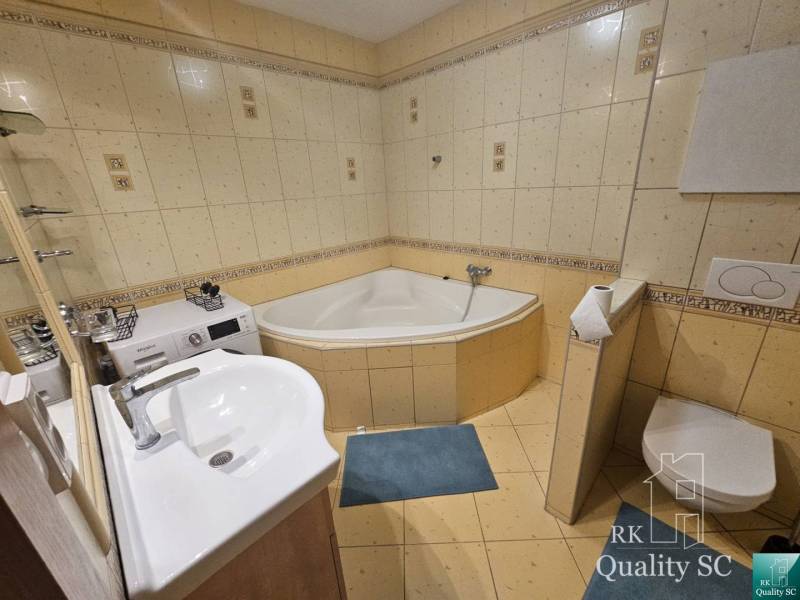 Bathroom with a bathtub, sink, washing machine, and toilet in a 3-room apartment.