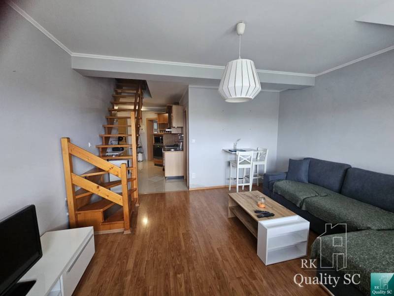 Living room in a 3-room apartment with a sofa, wooden stairs, and a television.