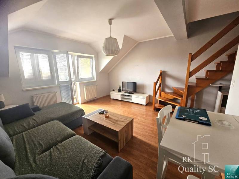 Living room with a sofa, table, and stairs in a three-room apartment.