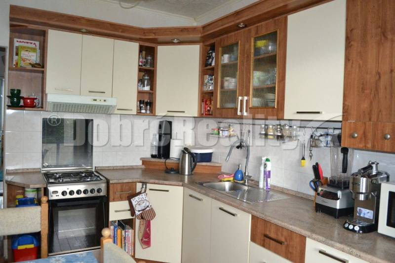 The kitchen in the 3-room apartment has wooden cabinets, a stove, and kitchen appliances.