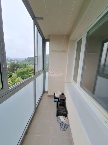 Enclosed balcony in a 3-room apartment with a view of greenery and surrounding hills.