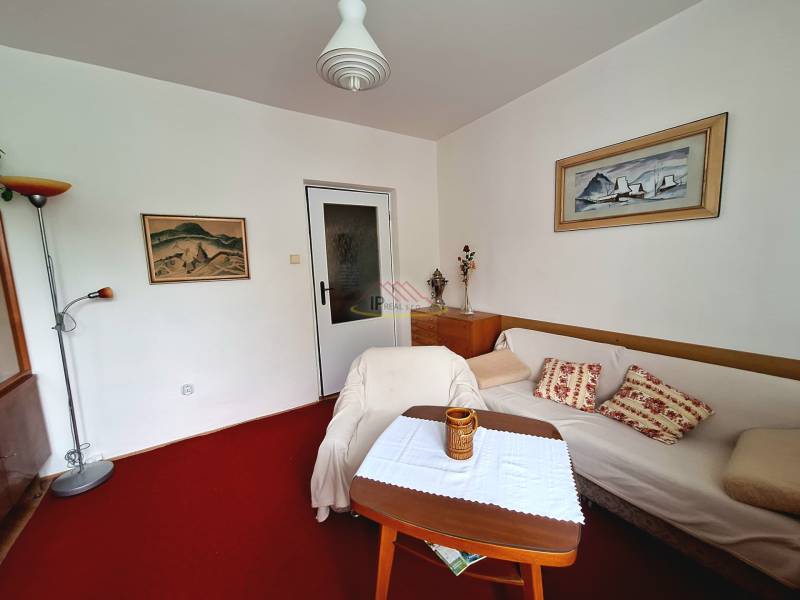 Living room in a three-room apartment with a white sofa and colorful decorations.