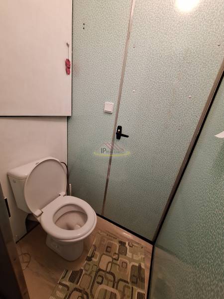 A bathroom with a white toilet and a carpet in a 3-room apartment.