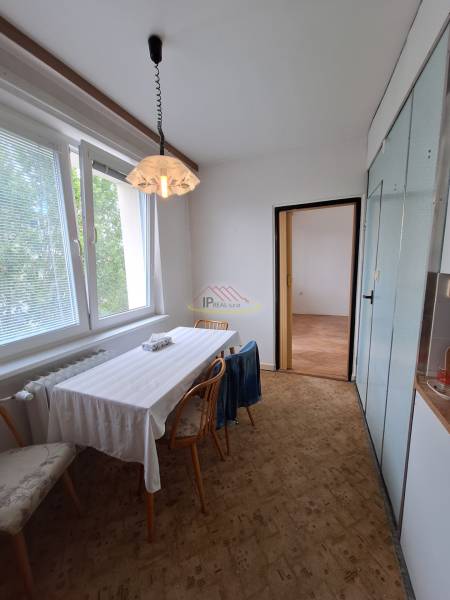Dining table with chairs in a 3-room apartment, minimalist furnishings, white walls.