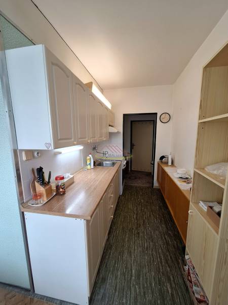 A narrow kitchen with a wooden countertop in a 3-room apartment, white cabinets, patterned floor.