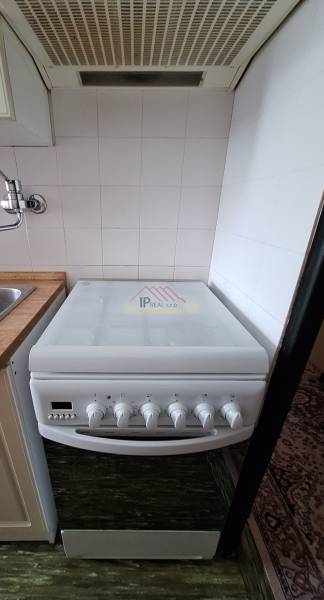 A kitchen in a 3-room apartment with an electric stove and a range hood.