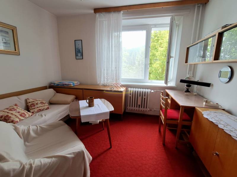 A room in a 3-room apartment with a couch, a table, and a desk under the window.
