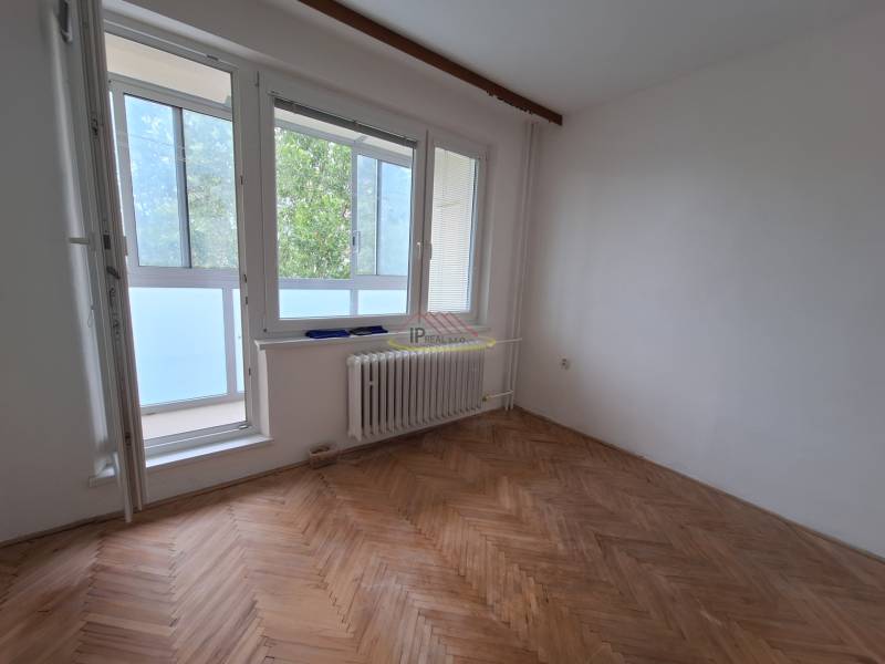 A room in a 3-room apartment with large windows and wooden flooring.