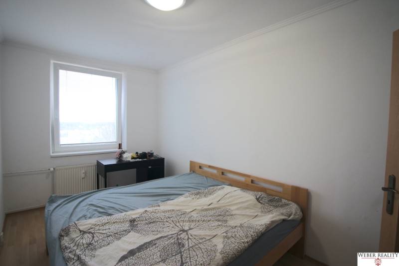 Bedroom in a 3-room apartment with a bed, window, and a small table.