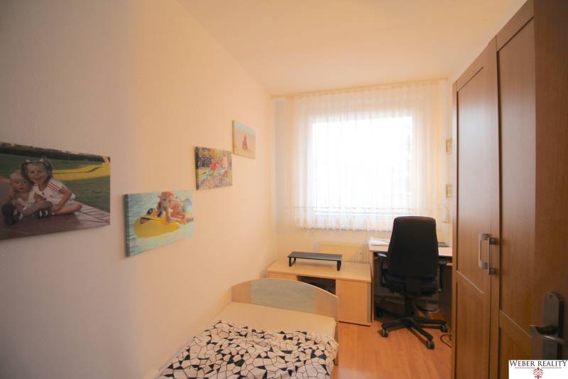 Children's room in a 3-room apartment with furniture, pictures on the wall, and a desk.