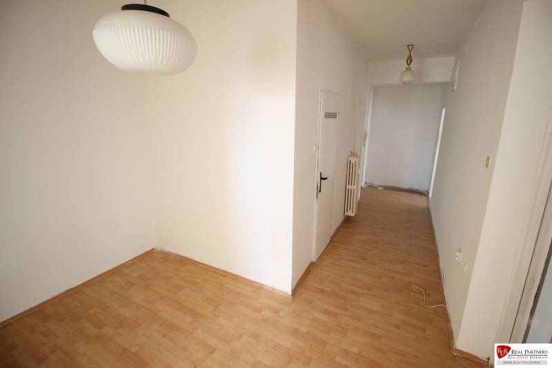 A hallway in a 3-room apartment with light, wooden flooring, and white walls.