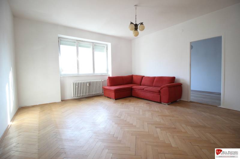 Living room in a 3-room apartment with a red sofa and wooden floor.