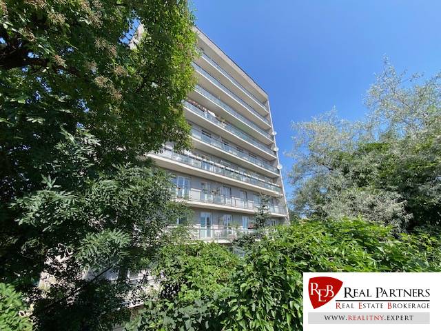 The image shows an apartment building on Na Hrebienku street, surrounded by greenery.