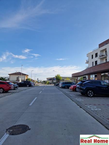 The road on Vtáčia Street in Senec, lined with buildings and parked cars, Gastro premises.