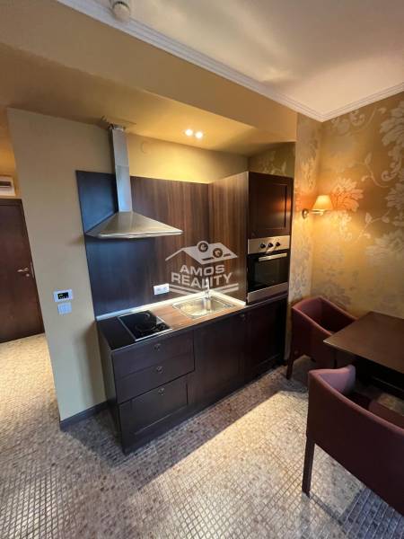 A kitchen in a holiday apartment with built-in appliances and stylish wallpaper.