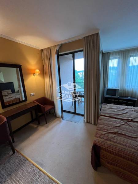 Bedroom of a holiday apartment with a view through the balcony doors, light furniture.