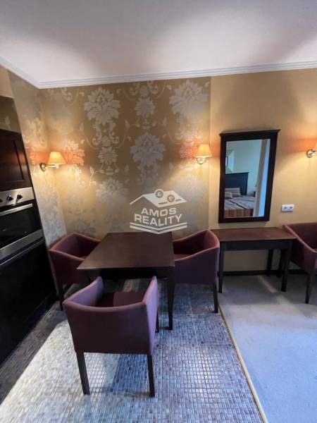 Dining room in a holiday apartment with a wallpapered wall, a coffee table, and two chairs.