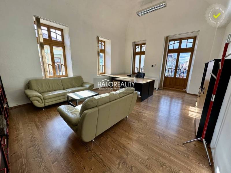 Offices with wooden floors, leather sofas, and large windows.