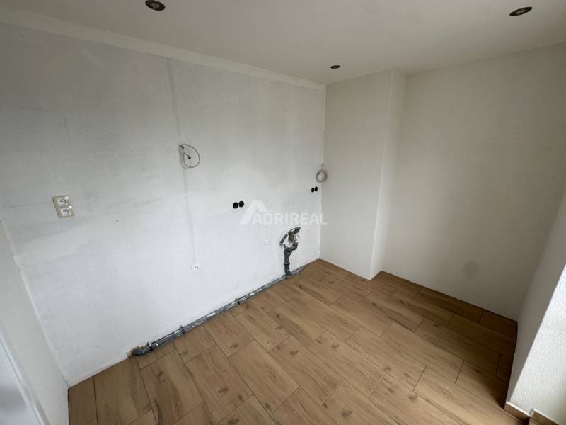 Unfurnished room in a 2-room apartment, light walls, wooden floor.