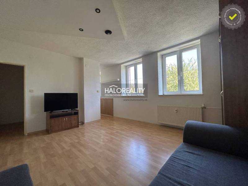 A bright living room with a TV and a sofa, part of a studio apartment.