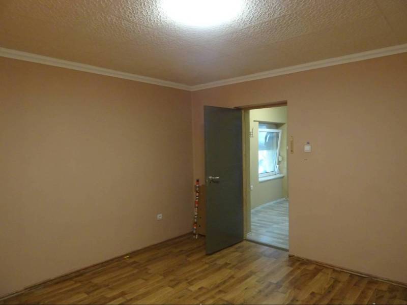 The interior of a room with brown walls and wooden flooring in a family house.