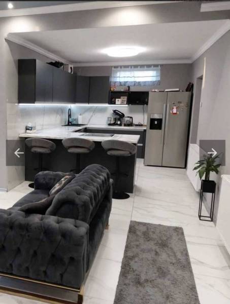 A kitchen in a family house with a bar counter, a sofa, and modern equipment.
