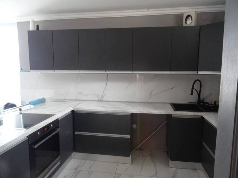 A kitchen in a family house with dark gray cabinets and a marble countertop.