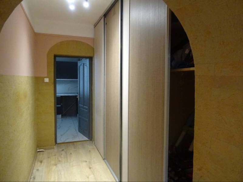 A hallway with a wooden floor, built-in wardrobe, and arched ceiling in a family house.