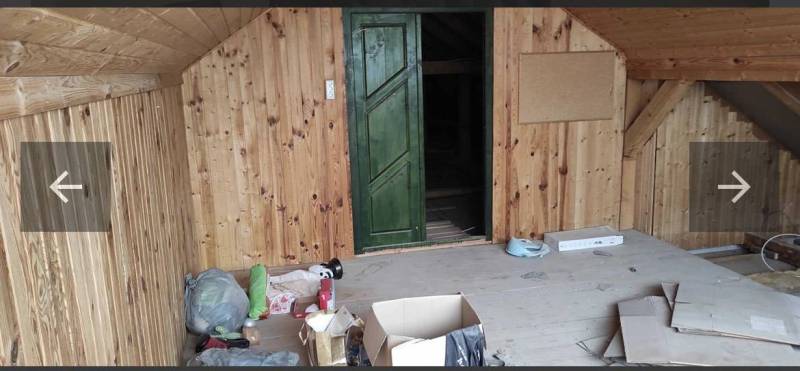 An attic room in a family house lined with wood, with stored boxes and bags.