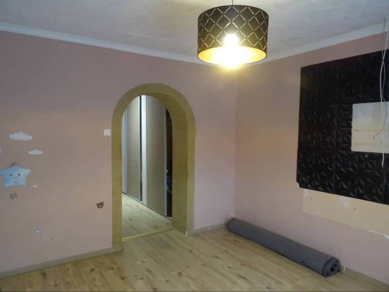 There is an empty room in the family house with an arched doorway and a pendant light.