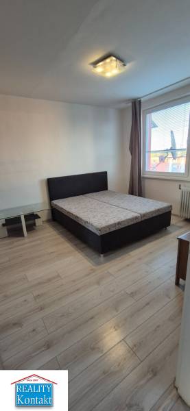 A bedroom in a studio apartment with a double bed and wooden flooring.