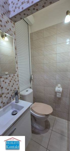 Bathroom in a studio apartment with light tiles and a toilet, sink with a faucet.