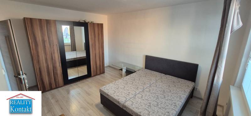Bedroom in a one-room apartment with a double bed, wardrobe, and glass table.