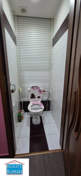 Bathroom in a studio apartment with a toilet and storage space with a roller shutter.